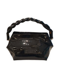 Frontal del bolso Adele resaltando su estructura hexagonal rígida y el acabado brillante tipo espejo del cuero charol negro