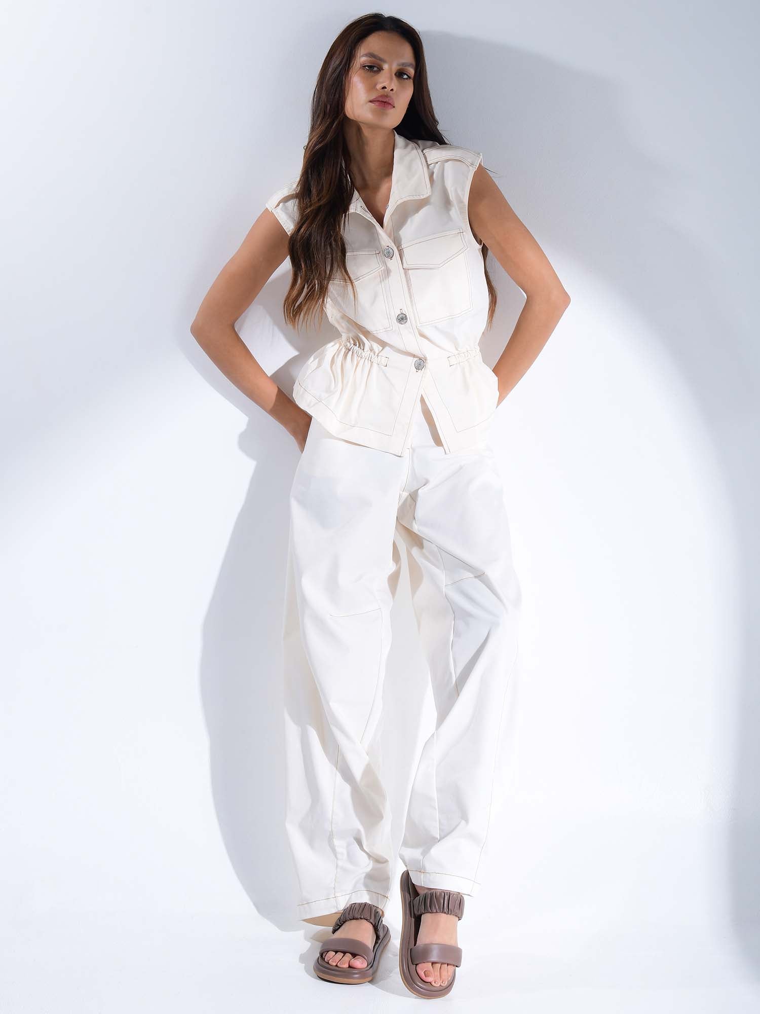 Modelo con outfit blanco casual luciendo las sandalias Ari marrón, destacando cómo el color tierra resalta sobre prendas claras