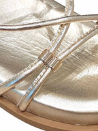 Primer plano del brillo metálico en las tiras doradas y el detalle metálico de ajuste en la sandalia Begonia