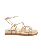 Perfil de la sandalia Begonia resaltando la suela plana y el sistema de amarre al tobillo con hebilla metálica dorada