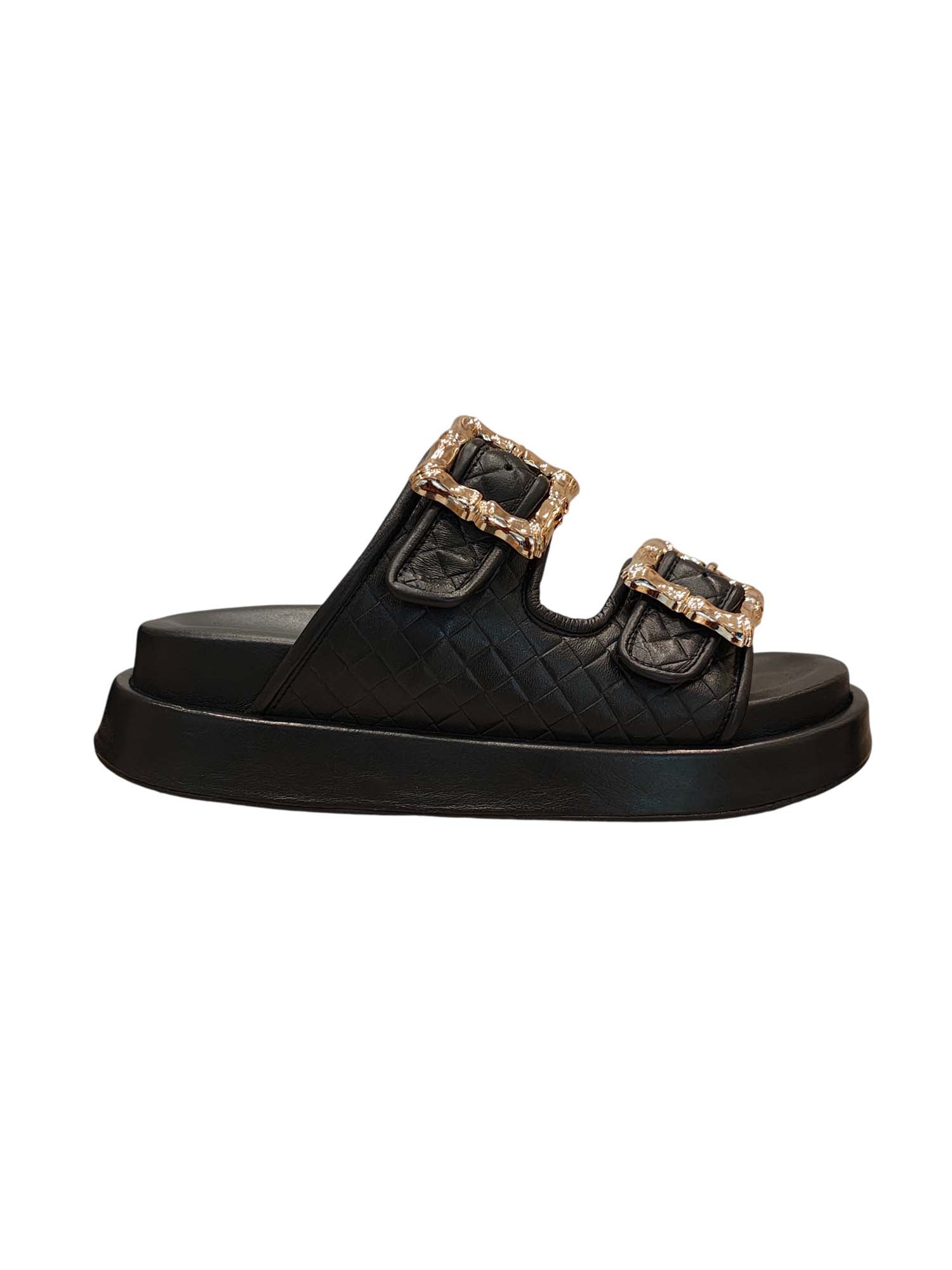 Perfil de la sandalia Gardenia resaltando la plataforma de altura media y la estructura robusta de las bandas de cuero negro