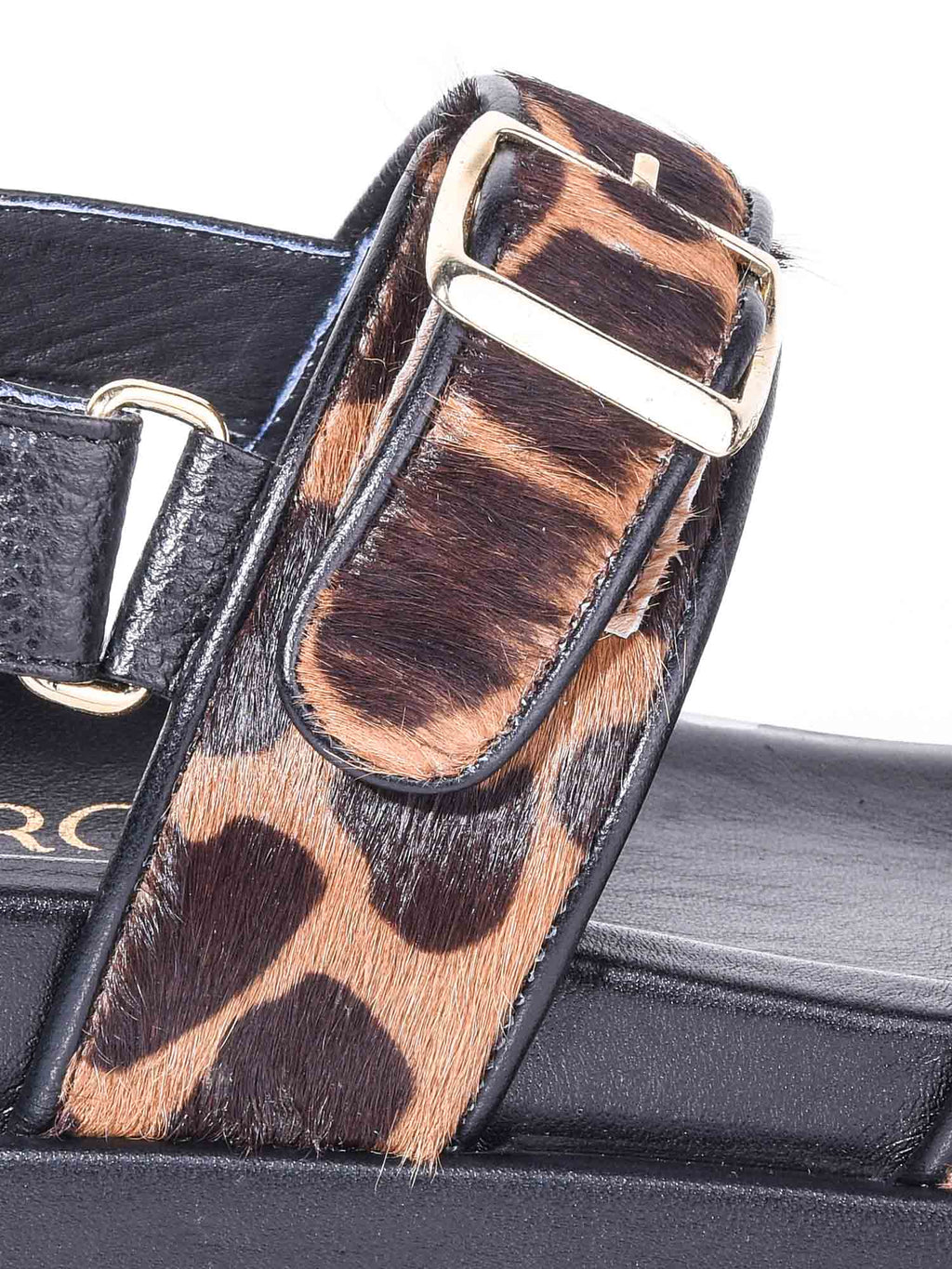 Primer plano del modelo India destacando el ajuste de velcro en el tobillo y la hebilla metálica sobre la textura animal print