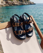Sandalia modelo India de Zuoro Shoes, diseño animal print puestas sobre una silla playera con una costa de fondo en la que resaltan todos sus acabados premum