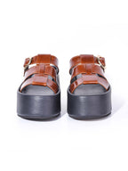 Vista frontal de la sandalia Alta marrón destacando el tono cálido del cuero en contraste con la base negra estructurada