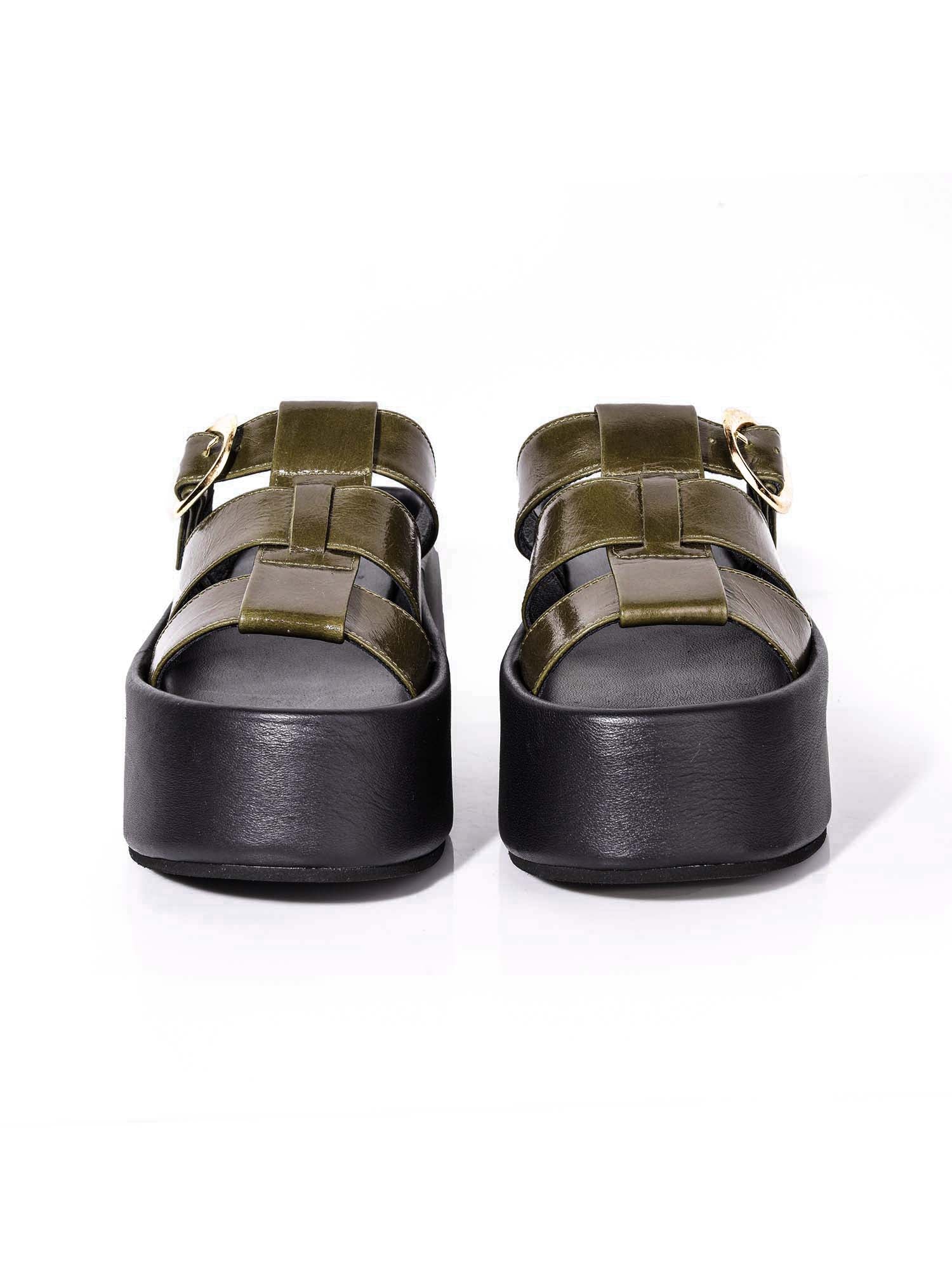 Vista frontal de la plataforma Alta resaltando el tono verde de la capellada y el sistema de ajuste con hebilla para un calce perfecto