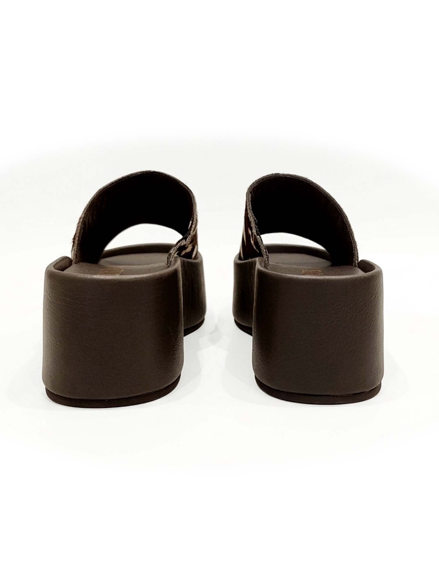 Vista posterior del modelo Nua, mostrando el talón abierto para un calce rápido y la robustez de la plataforma café