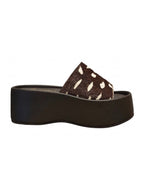 Perfil de la plataforma Nua resaltando la elevación uniforme de la suela y la estructura continua de la capellada en animal print