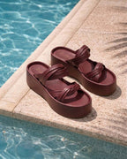 Imagen lifestyle de las plataformas Seda en color vinotinto en el borde de una piscina, capturando la comodidad y el carácter bohemio y versátil del diseño.
