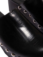 Primer plano de la capellada de la sandalia Tabata, resaltando la calidad del cuero negro y el acabado de lujo de los taches