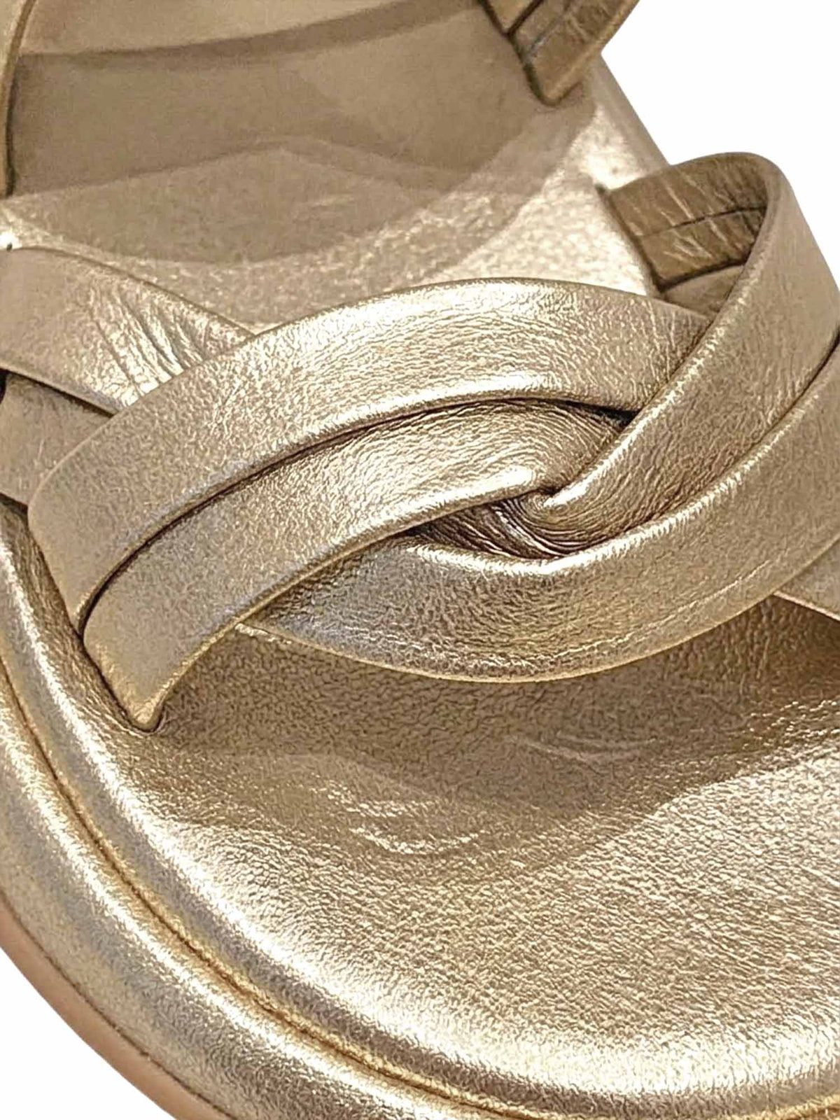 Primer plano del modelo Seda de Zuoro Shoes, enfocando la textura del cuero suave y el destello metalizado de las correas doradas entrelazadas