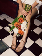 Tacón modelo Amane de Zuoro Shoes en color café, posando junto a un ramo de flores y destacando su trenzado a mano
