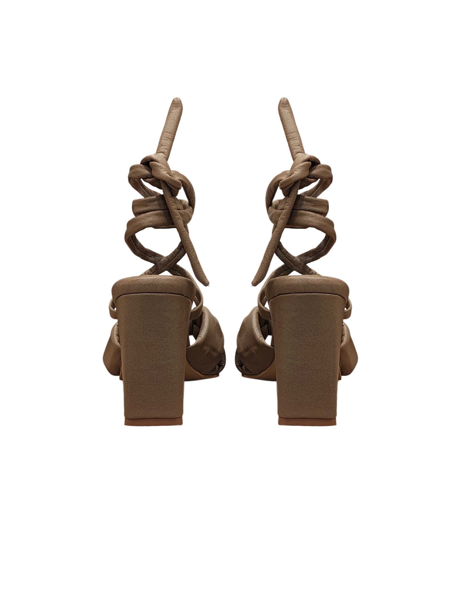 Vista posterior del modelo Arden, mostrando el tacón fino y la caída de las tiras de amarre en tono taupe premium